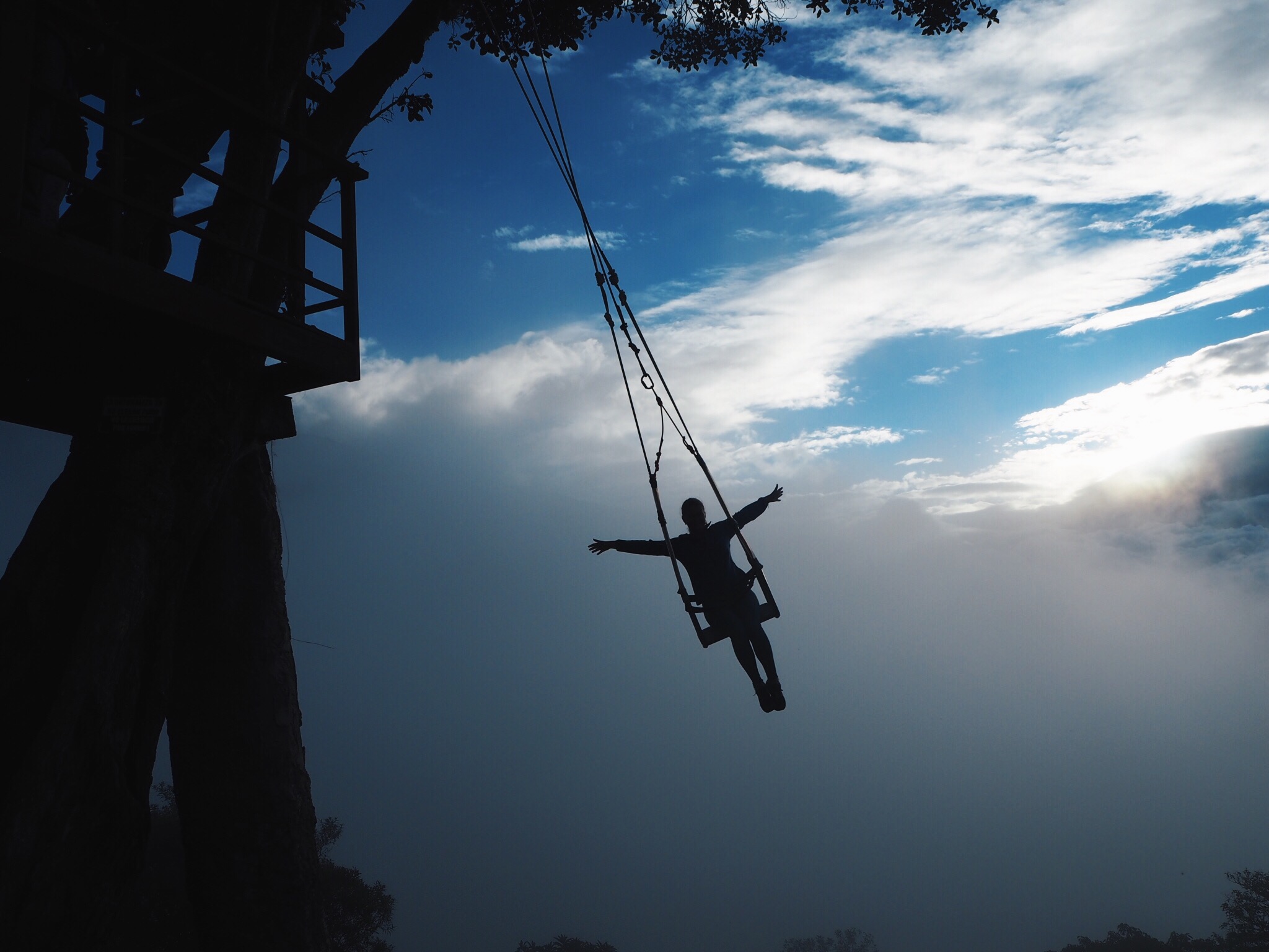 Girl on the swing at the end of the world in Banos, Ecuador